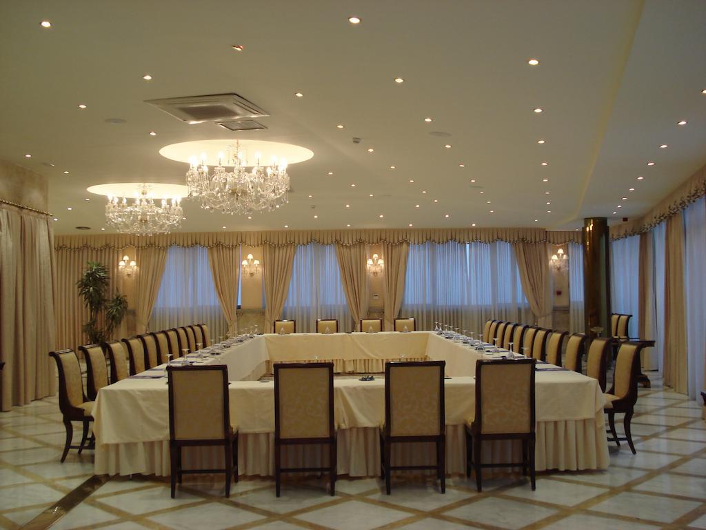 Hotel Alameda Palace Саламанка Экстерьер фото The photo shows a spacious and elegantly designed conference room. The room features a large rectangular table surrounded by numerous chairs, all arranged for a meeting or discussion. The table is covered with a white tablecloth, and the walls are ad